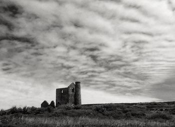 Built structure on field against cloudy sky