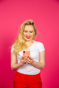 Young woman wearing red mask against pink background