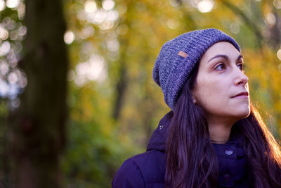 Close-up of woman wearing knit hat against trees