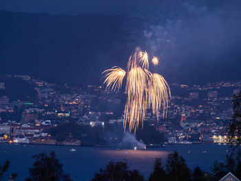 Firework display over illuminated buildings in city at night