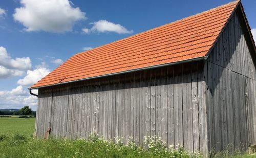 Plants growing by barn against blue sky