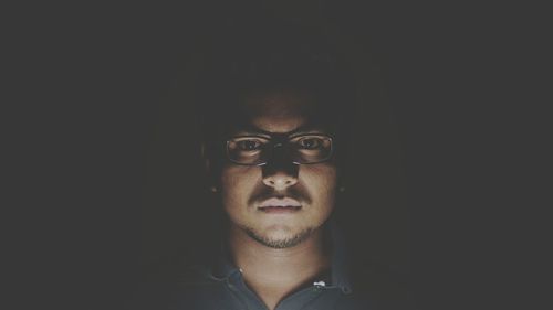 Portrait of man wearing eyeglasses in darkroom