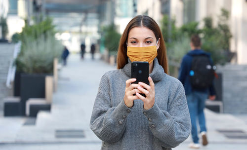 Portrait of man holding smart phone on street