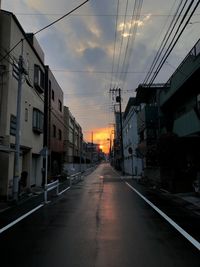 Road amidst buildings against sky during sunset