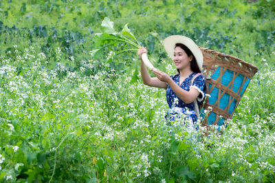 Full length of woman holding flowers in basket