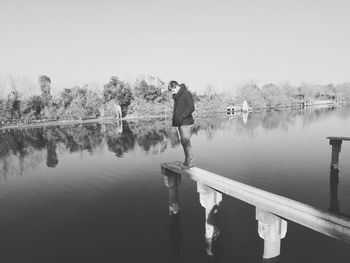 Man standing by lake against clear sky