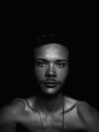 Portrait of young man against black background