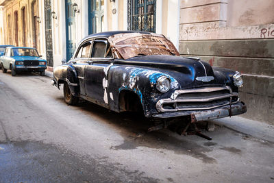 Rusty black vintage car with no windscreen on street