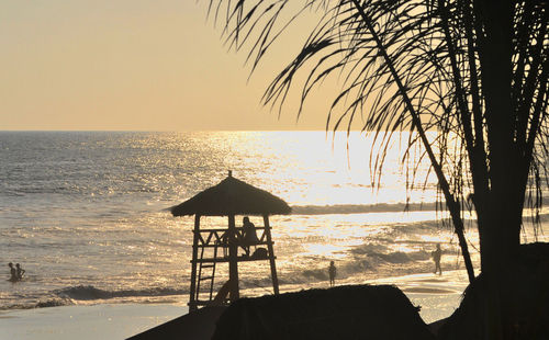 Lifeguard hut on beach against sky during sunset