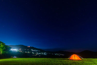 Scenic view of illuminated field against sky at night