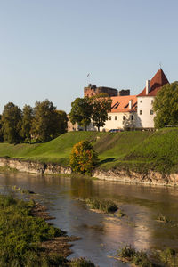 Houses by river against clear sky