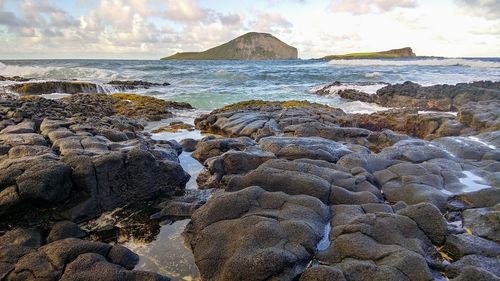 Rocks on beach against sky during sunset