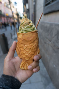 Point of view perspective of person holding taiyaki match  green tea ice cream cone. 