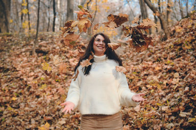 Full length of a young woman in autumn leaves