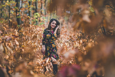 Portrait of young woman standing in forest during autumn