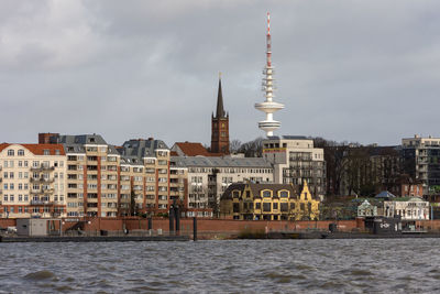 Buildings in city against cloudy sky