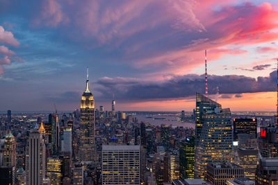 Modern buildings in city against sky during sunset