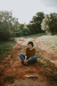 Woman sitting on dirt road