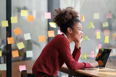 Side view of young woman using mobile phone in office