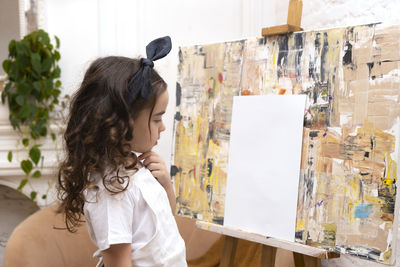 Lovely girl with paintbrush is thinking about a new drawing. little painting artist.