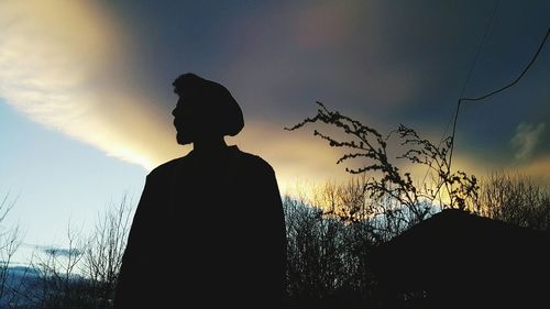 Silhouette of man standing by tree against sky