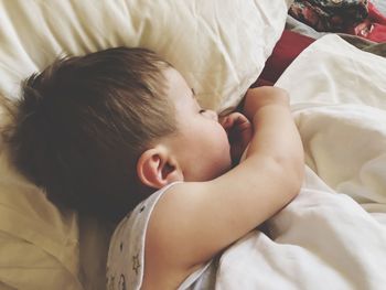 Boy sleeping on bed at home