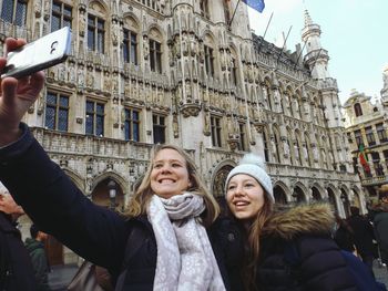 Smiling young women taking selfie in front of historical building