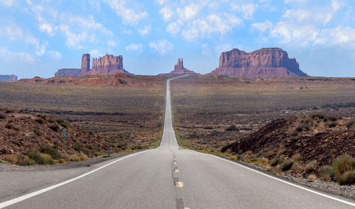 Road leading towards mountains against sky