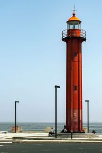 Lighthouse by sea against clear sky