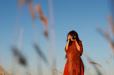 Woman photographing against sky