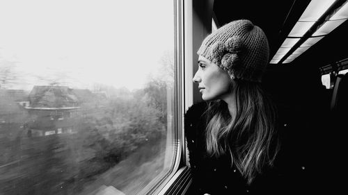 Thoughtful woman looking through window while traveling in train