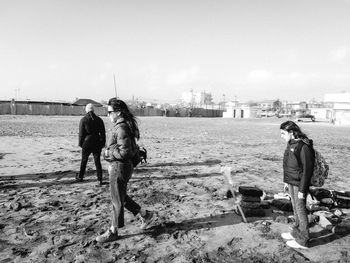 Rear view of people walking on beach against clear sky