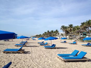 Lounge chairs on beach against sky