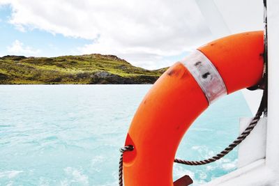 Close-up of orange boat in sea against sky