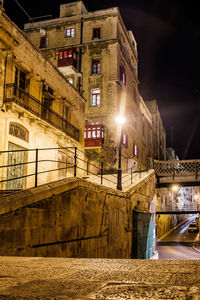 Illuminated buildings by river against sky in city at night