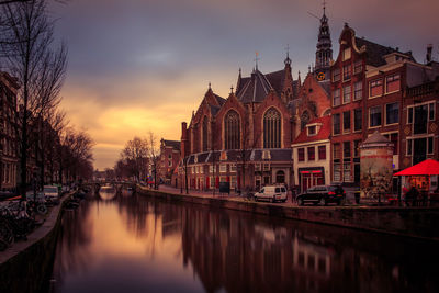 Buildings by canal during sunset
