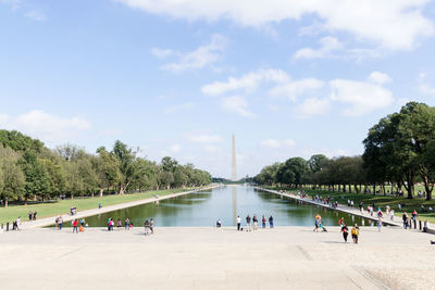 People by reflecting pool with washington monument in background