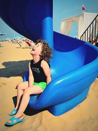 Full length of girl sitting on slide at playground