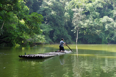 Man in boat on lake against trees