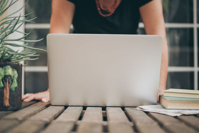 Midsection of woman using laptop on table