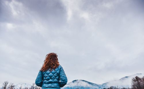 Rear view of woman with umbrella against sky during winter