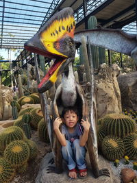 Portrait of boy sitting below bird sculpture