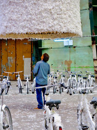 Rear view of man standing by bicycles outdoors