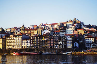 Buildings by river against clear sky