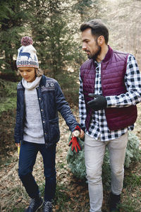 Father talking while son holding branch in forest