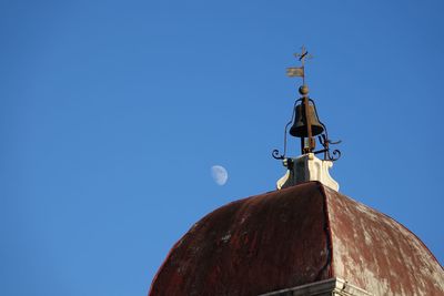 Low angle view of cross on roof of building against clear blue sky