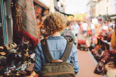 Rear view of woman walking through street market stalls in city