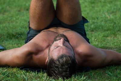 Shirtless man exercising on grass at park