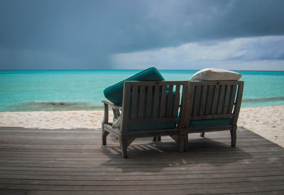 Empty chairs on beach against sky