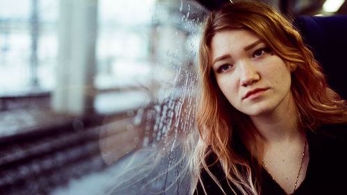 Portrait of a woman sitting in a subway leaning against a window